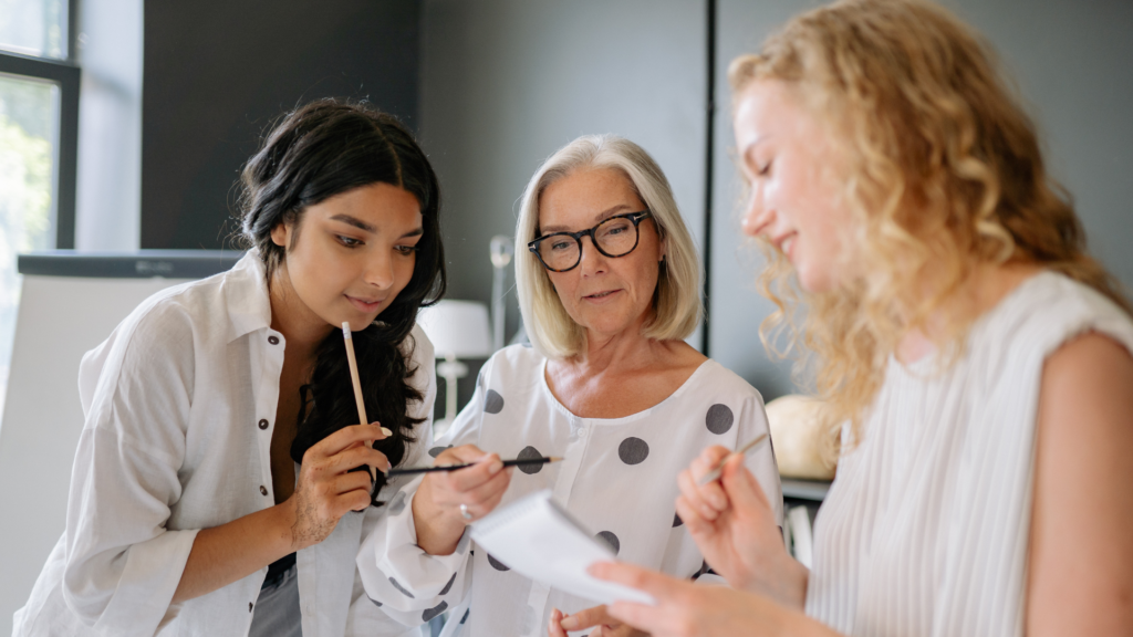 women having a discussion in a modern office setting, reviewing documents about implementing a membership program that offers clients monthly or annual subscriptions for exclusive access to services and locations.