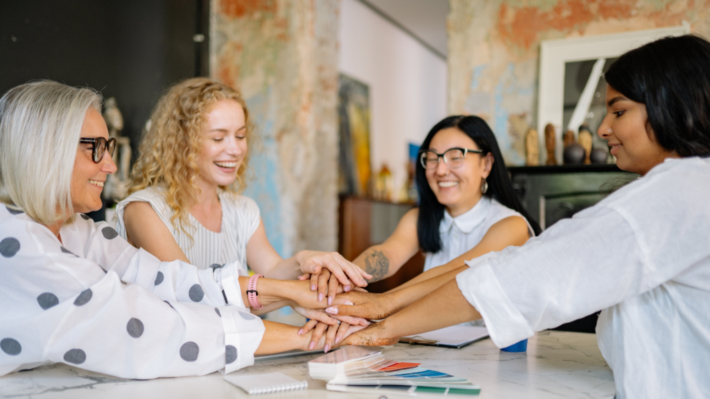 women in a creative studio setting discussing a partnership strategy with photo and film production agencies, aiming to increase bookings and expand their audience through special rates and long-term collaboration packages.
